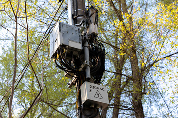Electrical and communication equipment mounted on a utility pole with visible cables and a 220VAC...