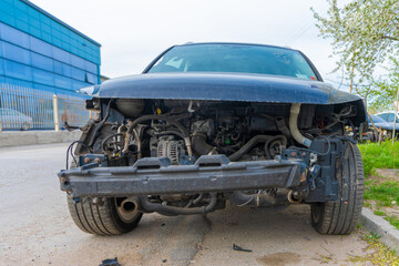 Frontal view of a car with its bumper and front components removed, exposing engine, hoses, and...