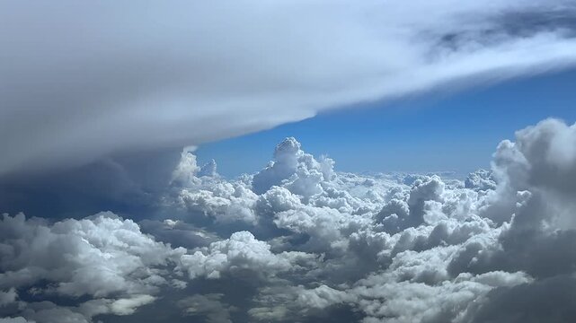 A pilot&rsquo;s view in a real time flight surrounded by massie and threatening storm clouds, with a soothing blue and sunny sky at the back. Ultra-realistic. 4K