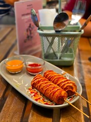 A classic American fast food, the Corn Dog (Hot Dog),typically deep-fried and skewered, often found in carnivals and fairs.