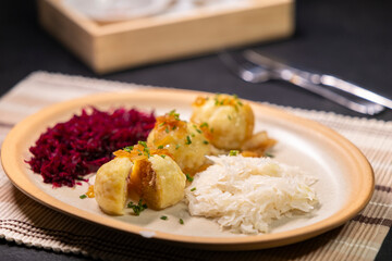 Potato dumplings filled with minced meat, topped with fried onions, served with sauerkraut and red cabbage