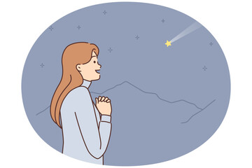 Dreaming woman with palms clasped in front chest looks at shooting star and makes wish