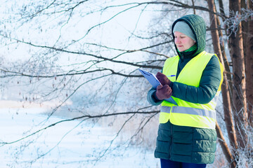 Female ecologist inspects trees. Eco volunteer. Forestry engineer works in winter. Inspector...
