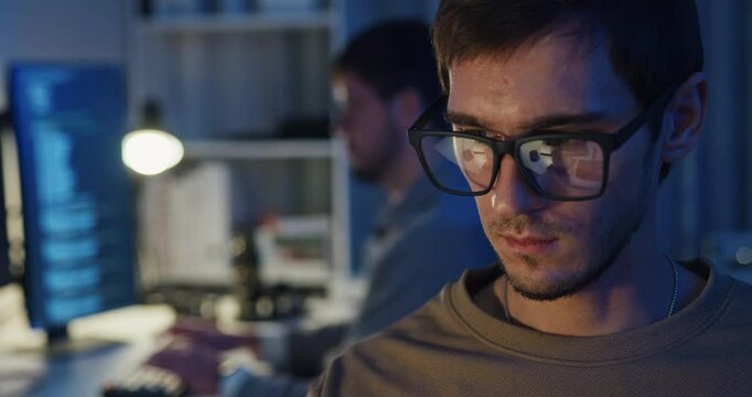 Closeup team adult male freelance work late typing write prompt AI bot app program nomad terminal code at office night. Artificial intelligence dashboard, robotics, user interface, machine learning.