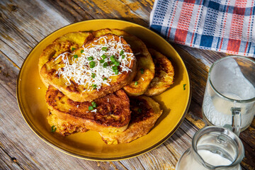 Fried bread with egg and milk cream or white cheese on top on a wooden table.