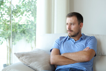 Fototapeta premium Pensive sad man looking through a window on a couch