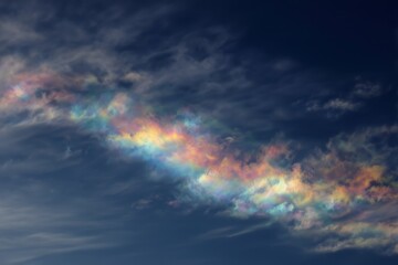Rainbow Iridescence Forming in Sunlit Clouds Against Blue Sky