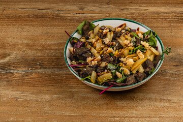 Savory mixed salad with grilled meat and nuts in bowl