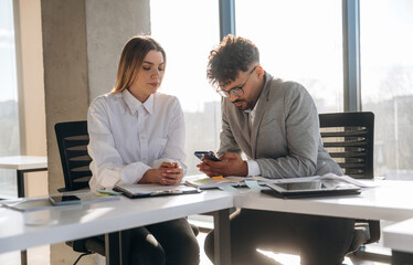 Cooperation, working on project. Man and woman are indoors in modern building