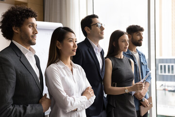 United in diversity. Successful confident multiethnic millennial business team posing for portrait stand in row look in the same direction. Ambitious young professionals feel bonding synergy at work