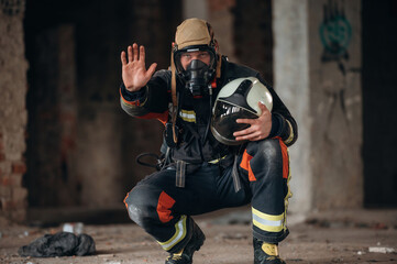 By the help of air mask. Firefighter in professional equipment is indoors in abandoned building