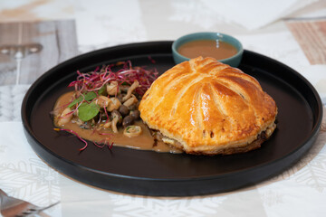 A plate of chicken wellington stuffing with mushroom and spinach with poultry sauce, shitake mushroom, beetroots sprout as a side dish.