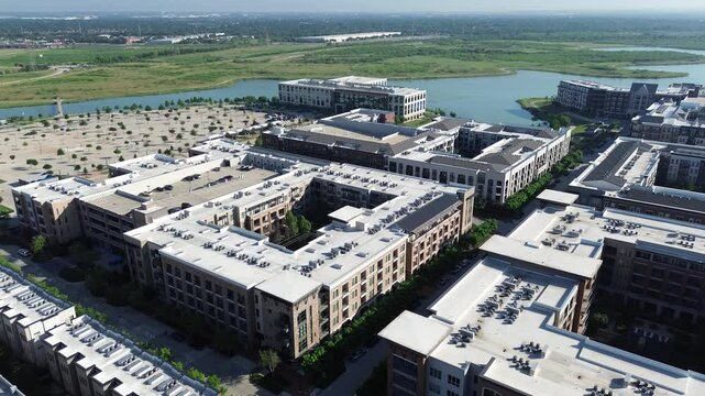 Flat roof commercial HVAC unit packages at modern lakeside apartment building complex with tree lined street, walking trails, pool, master-planned Cypress Waters suburb Dallas Fort Worth metroplex