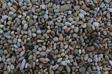 Smooth round pebbles texture background. Pebble sea beach close-up, dark wet pebble and gray dry pebble. natural gravel, texture from gravel. Gravel texture. Pebble stone background. Granite gravel
