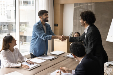 Negotiation success. Glad excited millennial male partner investor shake hand of business associate...