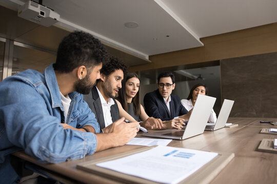 Useful advice. Experienced young colleague team leader professional expert analyst help teach diverse multiracial department staff interns gathered together by computers explain work in corporate app