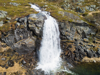 Aerial drone perspective: majestic Myfallet waterfall in Norway, its powerful cascades carving through the rugged, rocky northern landscape.