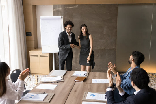 Glad to welcome in team. Happy smiling professional male boss leader introduce young female newcomer to diverse international department workforce handshaking new employee on staff boardroom meeting