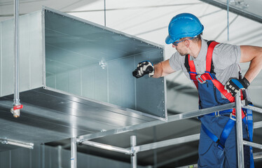 Skilled HVAC Worker Installing Ductwork in a Commercial Building During Daylight Hours