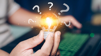 Businessman holding glowing light bulb and question mark for creative thinking idea and problem solving. idea and Glowing light bulb and question mark concept.