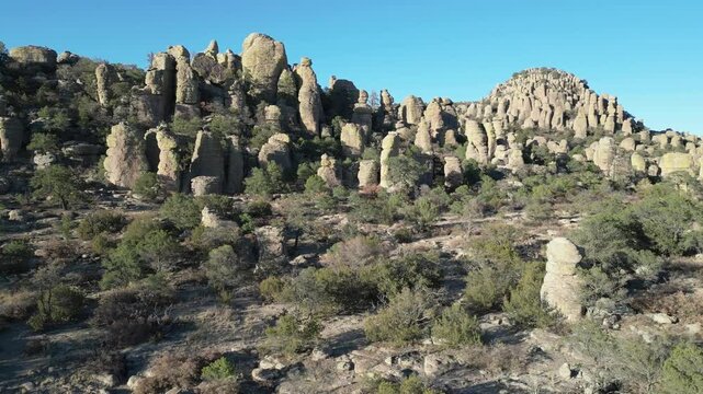 Rock spires and dry shrubs under clear sky in Valle de los Monjes, Creel, Chihuahua