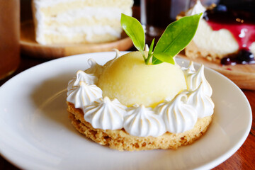 Fresh homemade lemon tart and vanilla cream decorated on white dish in cafe