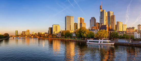 Golden sunrise view of the skyline of Frankfurt, Germany, with banking skyscrapers and reflections in the River Main