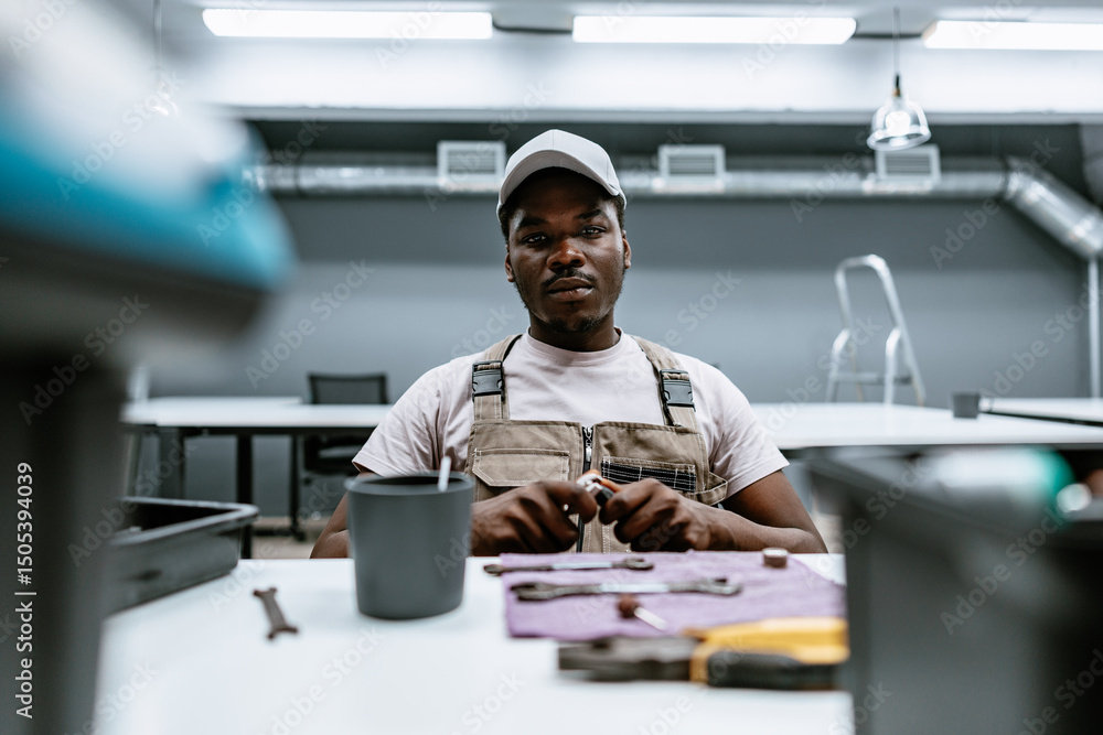 Poster skilled technician performing assembly work in a modern workshop while focused on tools and material