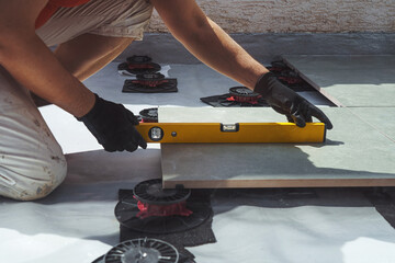 Laying tiles concept. Tiler, spatula and glue when laying tiles with close up hands. Stilts and...