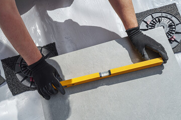 Laying tiles concept. Tiler, spatula and glue when laying tiles with close up hands. Stilts and...