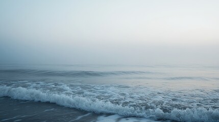 Fototapeta premium Calm and foggy morning at the sea with gentle waves and a soft breeze, creating a peaceful and reflective ambiance