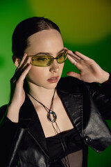 Chic young woman stylishly posing in black attire against a vibrant green backdrop