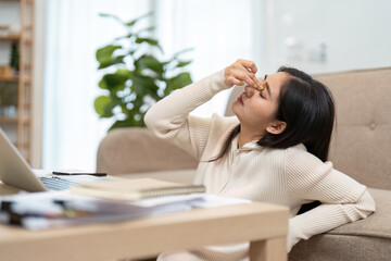 Work Stress and Relief. A woman at home rubbing her forehead in frustration while working on her...