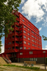 Bench in front of bright red apartment complex building in Almere, Flevoland. Real estate housing market in The Netherlands