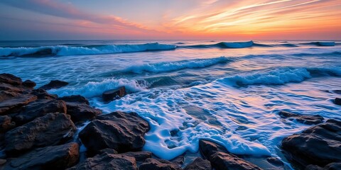 Obraz premium Ocean waves crashing on rocky shore at sunset, power, energy