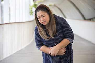 Southeast Asian woman with stomach ache, concept image of menstrual period cramp, abdominal pain,...