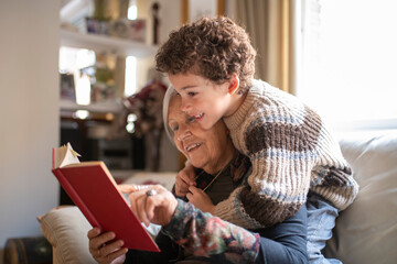 Grandmother reading a book with grandson hugging her