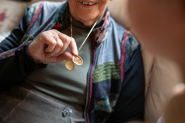 Elderly woman showing golden necklace with grandchild photo in medallion