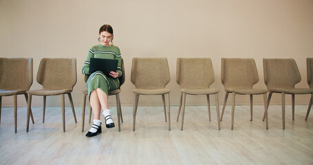 Laptop, hiring and business woman in waiting room at startup for content writing. Computer, recruitment and person prepare for interview, job search or reading resume for creative opportunity online