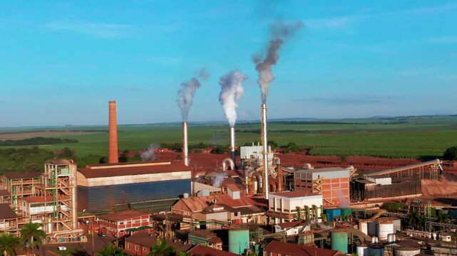 Drone aerial landscape of steam fumes coming from steel turbines at ethanol production plant factory buildings and facility in rural countryside Brazil South America industry processing warehouse