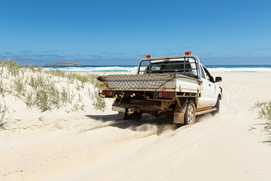 Four wheel drive ute driving onto beach