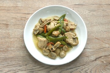 stir fried green pea and straw mushroom with pork in soybean sauce on plate