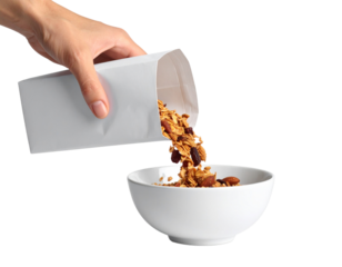 A hand pours granola from a white packet into a white bowl against a black background.