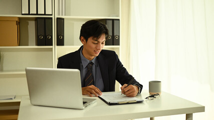 Young Businessman Reviewing Documents at His Desk, Focused Business Planning