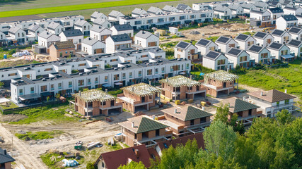 Rows of single-family houses on the city outskirts, featuring solar panels and green gardens,...