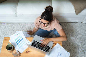 Young woman freelance worker small startup company business owner calculating tax return with data...