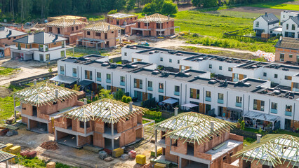 Rows of single-family houses on the city outskirts, featuring solar panels and green gardens,...