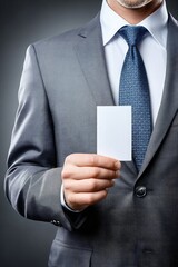 A man in a suit holds a blank business card, ready for branding or personal information, against a dark background.
