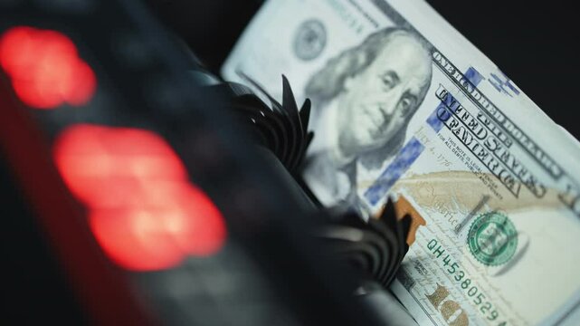 An automated money counting machine sorting $100 bills with Benjamin Franklin&rsquo;s image. Symbolizing financial savings, budgeting, and cash management.
