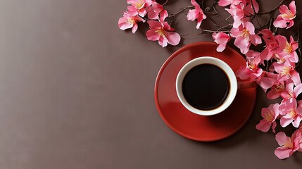   A red saucer holds a cup of coffee beside a pink-flowered branch